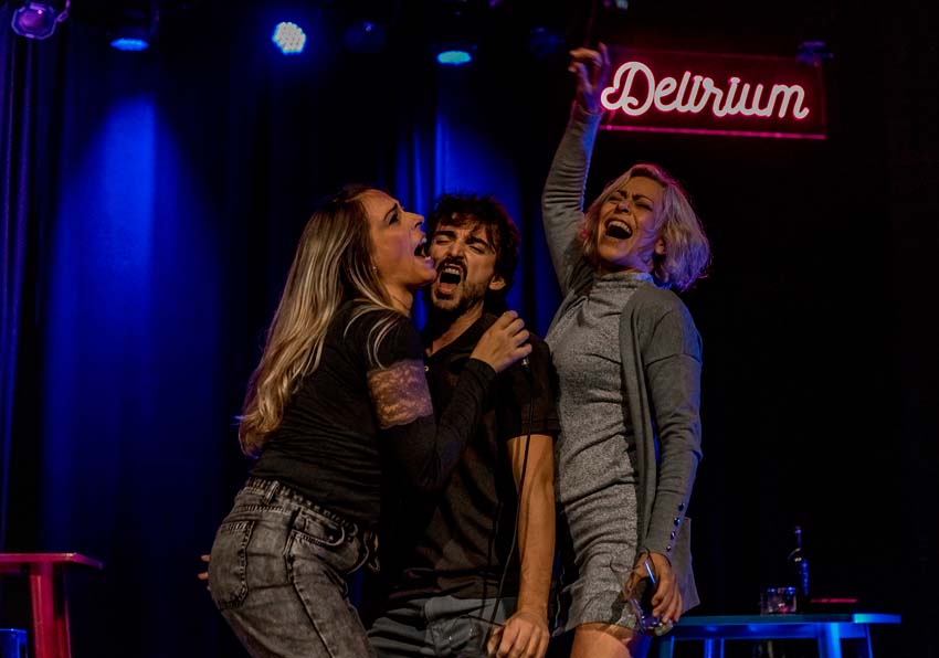 Dos mujeres y un hombre bebiendo y gritando